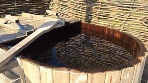 Ein Holzfass mit Metalleinsatz, gefüllt mit Wasser und Holzscheiten.