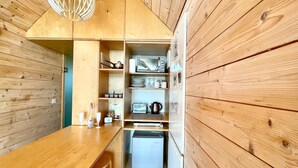 Eine kleine Küche mit Holzwänden, einem Holztisch und einer eingebauten Mikrowelle.