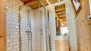 A modern bathroom with a glass-enclosed shower, white tiled walls, and wooden accents. - Lushna Petite 12 at Lee Wick Farm Glamping (Clacton on Sea)