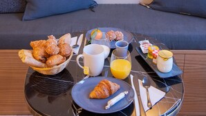 Ein Frühstückstisch mit Croissants, Orangensaft und einem Nutella-Glas.