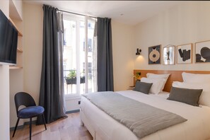 A hotel room with a bed, a chair, a window with curtains, and wall art. - Tinah Paris Aboukir (Paris)