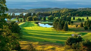 Un campo de golf con un estanque, árboles y vistas del paisaje circundante.