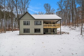 A two-story house with a balcony on the second floor, surrounded by trees and snow. - Luxury Boyne Mountain Ski-In/Out with Hot Tub (Boyne City)