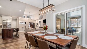 Un comedor amplio con una mesa de madera, sillas marrones y una lámpara colgante.