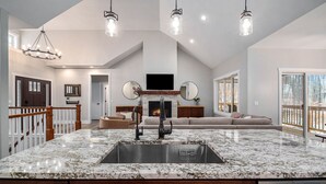 Una cocina amplia con una isla grande, una chimenea y un área de estar con sofá y televisor.