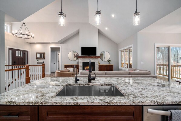 A spacious kitchen with a large island, a fireplace, and a living area with a sofa and TV.
