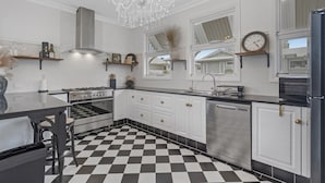 Une cuisine moderne avec un sol à carreaux noirs et blancs, des appareils électroménagers en acier inoxydable et un lustre.