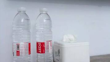 Two water bottles and a tissue box on a wooden surface against a white wall.
