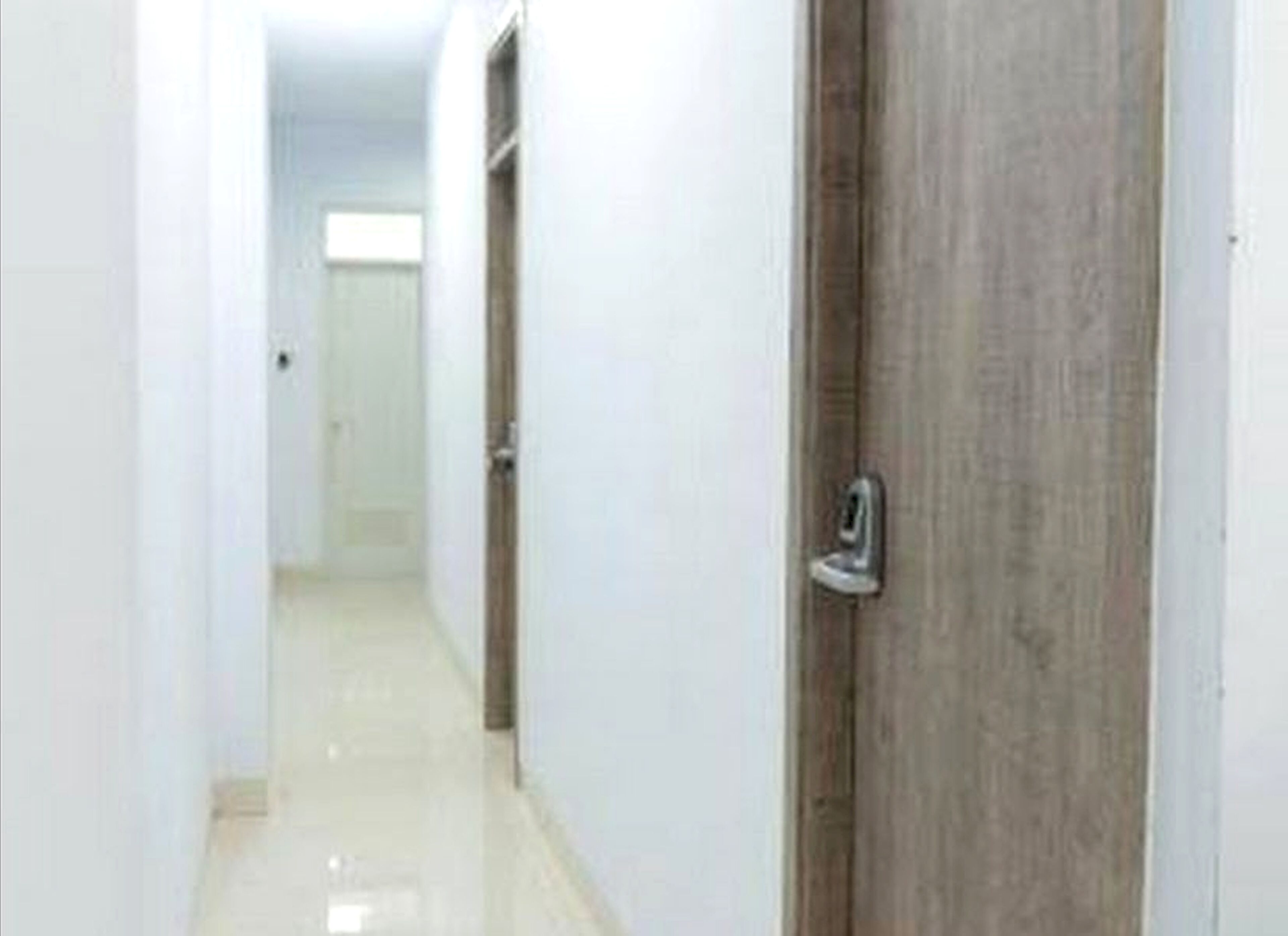 A hallway with a wooden door and a white wall.