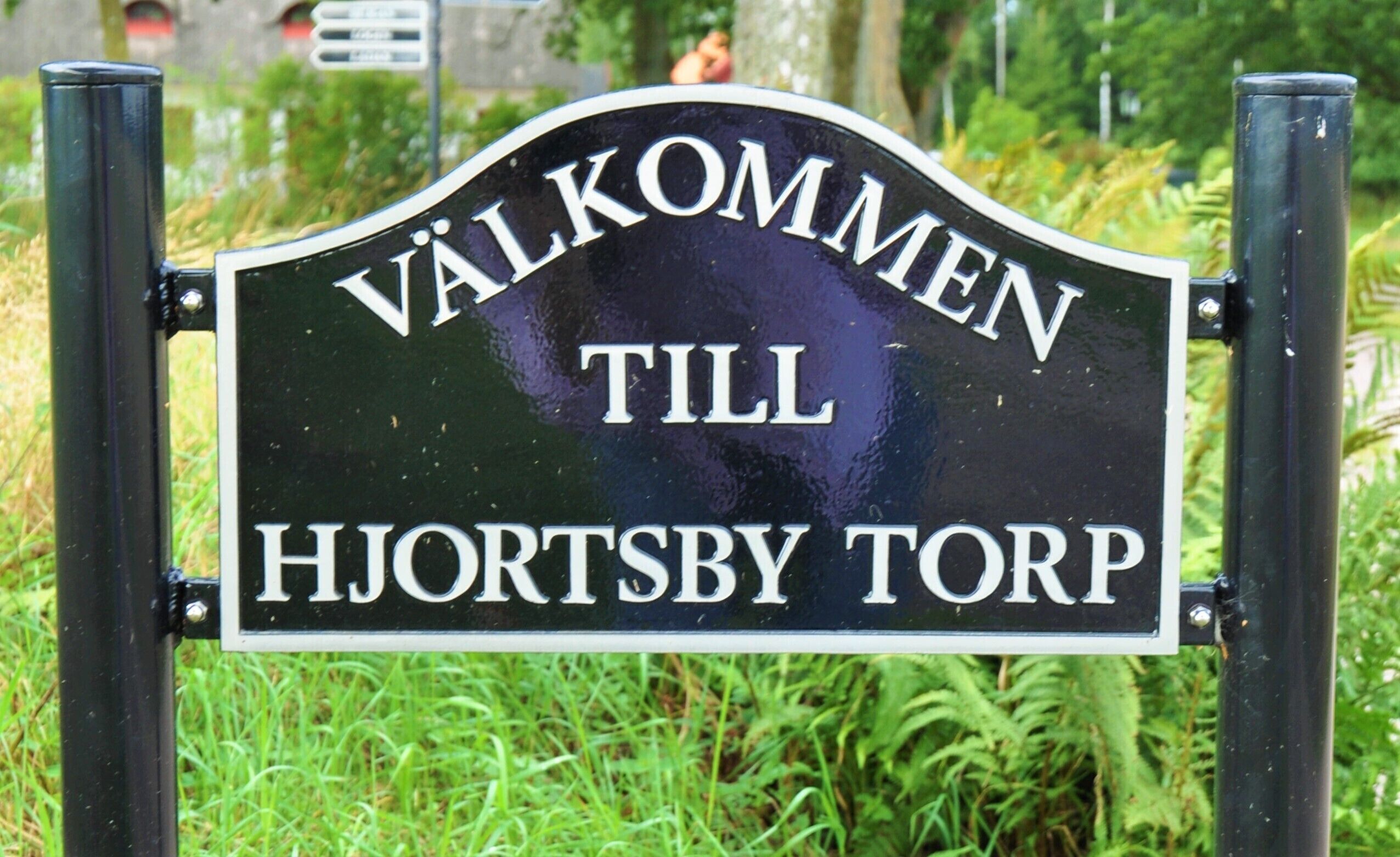 A sign with the text "VÄLKOMMEN TILL HJORTSBY TORP".