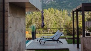 A modern outdoor patio with a pool, lounge chairs, and a view of mountains. - Luxury villa with swimming pool, sauna and jacuzzi (Baska)