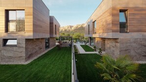 A modern two-story building with a symmetrical design, featuring large windows and a well-maintained lawn. - Luxury villa with swimming pool, sauna and jacuzzi (Baska)
