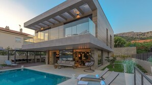 A modern two-story house with a swimming pool, outdoor seating, and a view of the surrounding landscape. - Luxury villa with swimming pool, sauna and jacuzzi (Baska)
