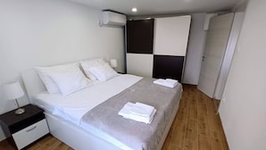 A modern hotel room with a large bed, a bedside table, and a wardrobe. - Modern equipped apartment in the  center of Baška, near the sea (Baska)