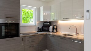 A modern kitchen with a built-in oven, microwave, coffee maker, and a sink with a modern faucet.