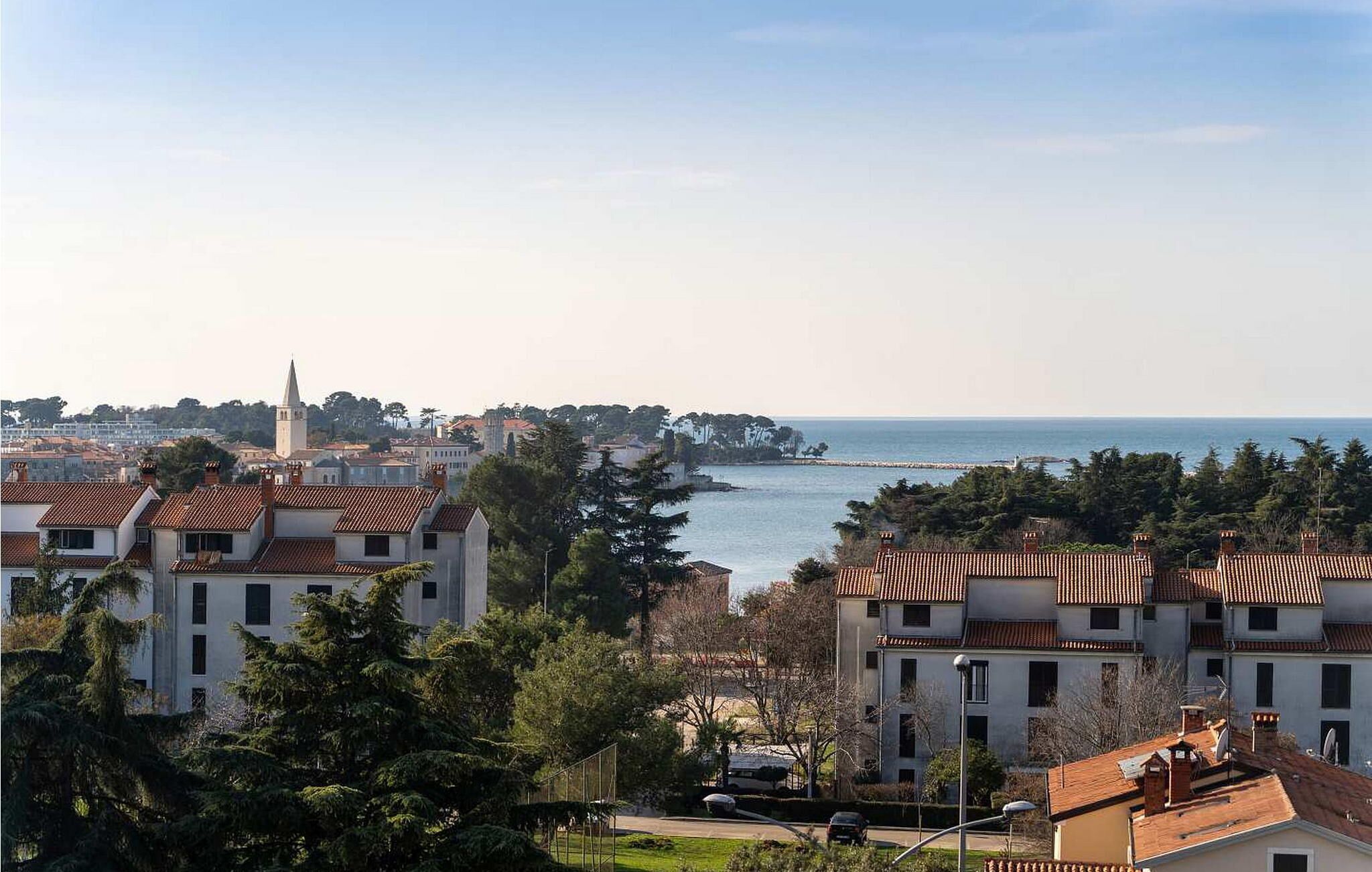 Eine Küstenstadt mit traditioneller Bebauung, einem markanten Kirchturm und Blick auf das Meer.