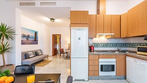 Eine moderne Küche mit Holzausstattung, einem Kühlschrank, einem Backofen und einem Geschirrspüler.