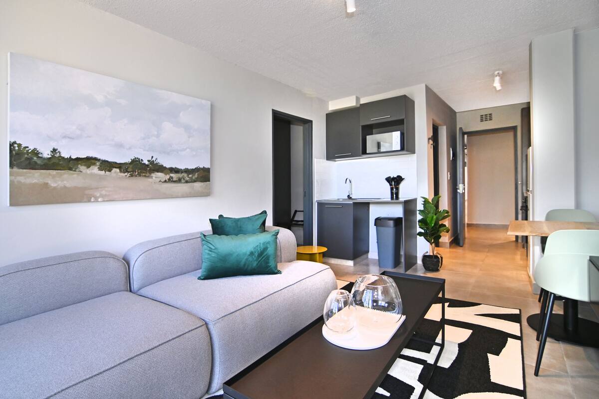 Een moderne woonkamer met een grijze bank, een salontafel en een schilderij aan de muur.