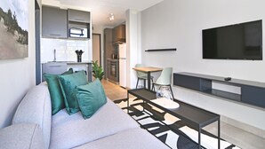 A modern living room with a sofa, a coffee table, and a TV mounted on the wall.
