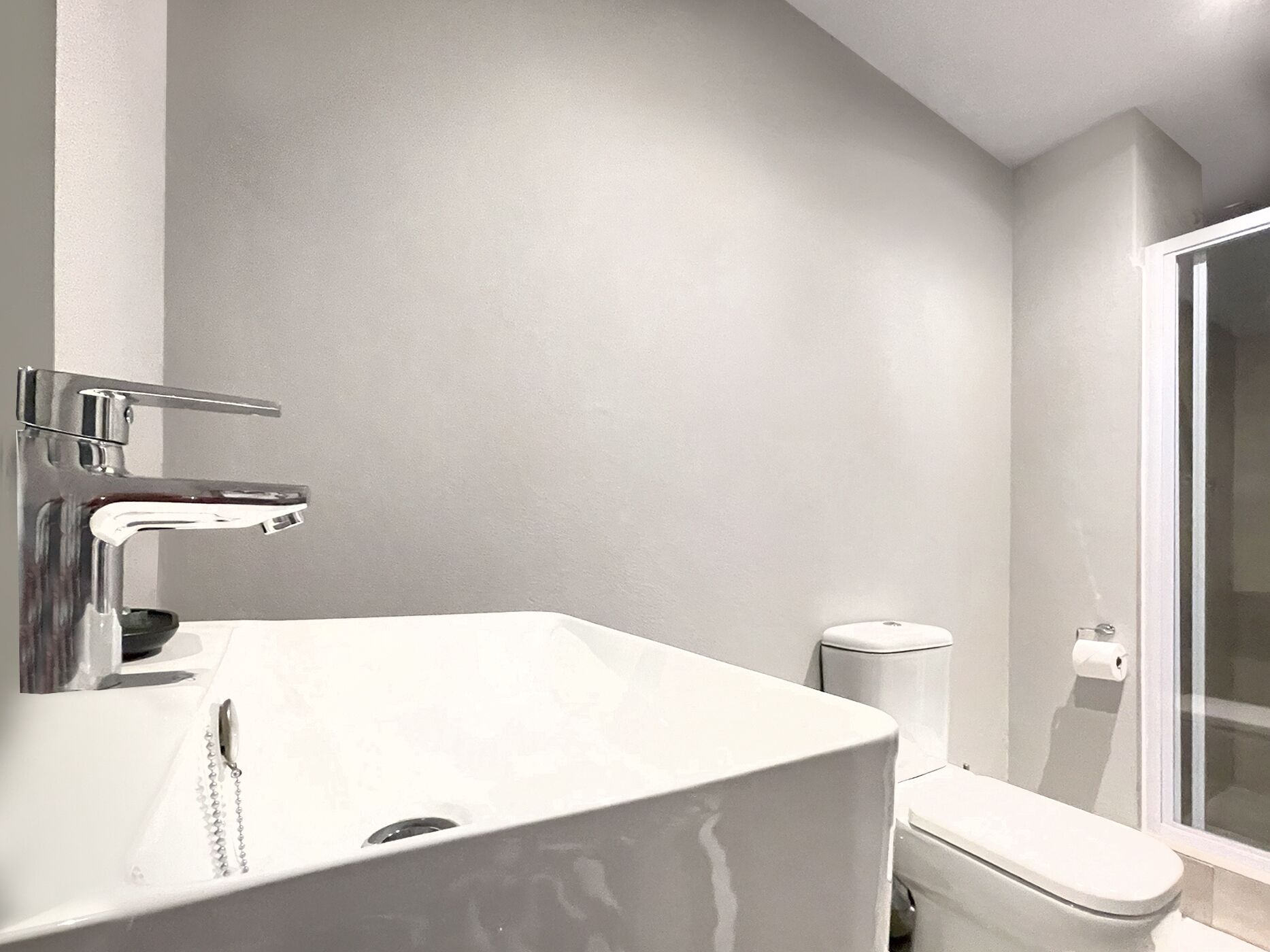 Une salle de bain moderne avec un lavabo blanc, un robinet chromé et des toilettes.