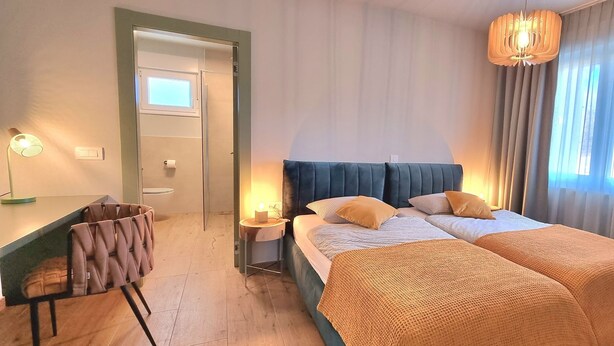 Quarto de hotel com cama, mesa de cabeceira, luminária, poltrona e vista para o exterior.