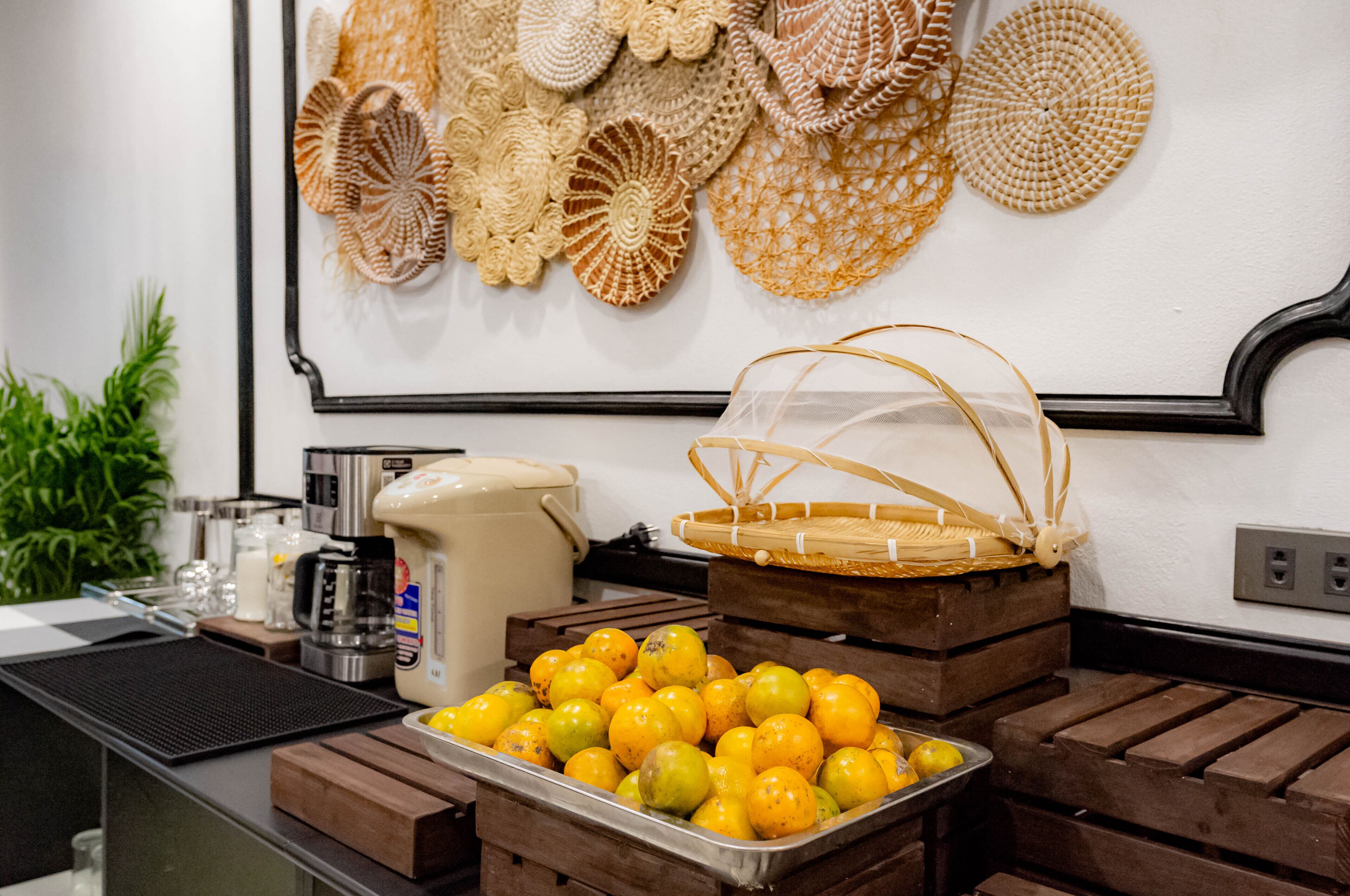 A buffet setup with a tray of lemons, a coffee maker, and a basket on wooden crates.