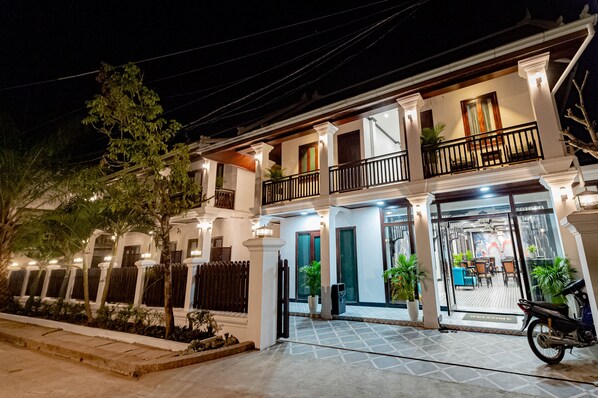 A two-story building with a balcony, potted plants, and a motorcycle parked in front. - Palm Golden Luangprabang Hotel (Luang Prabang)