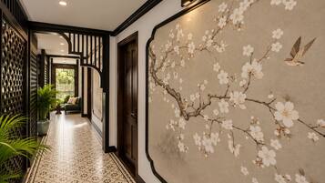 A hallway with a patterned floor, a wall with a floral mural, and a door leading to another room.
