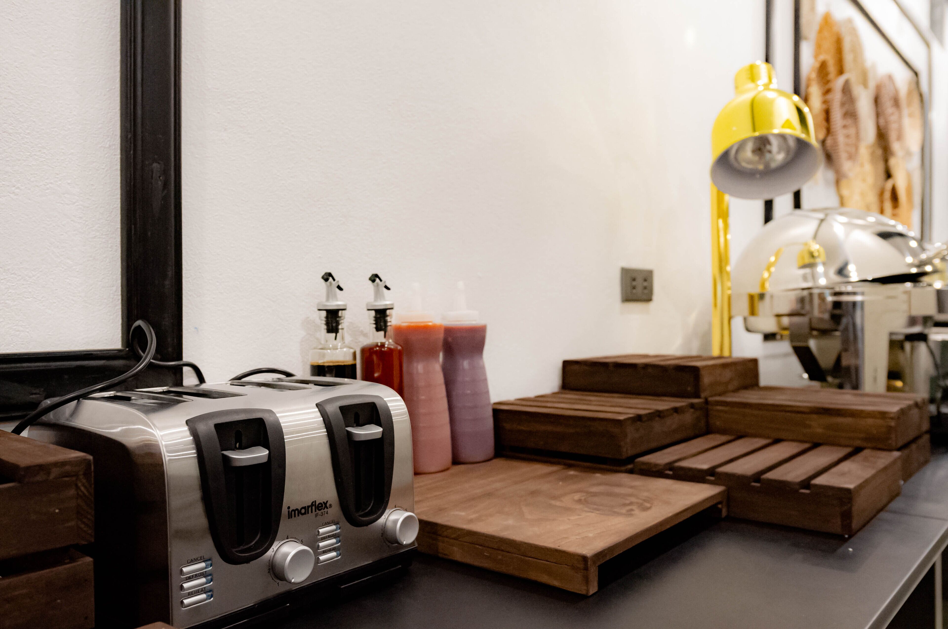 Una encimera de cocina con un tostador, botellas de condimentos y tablas de cortar de madera.