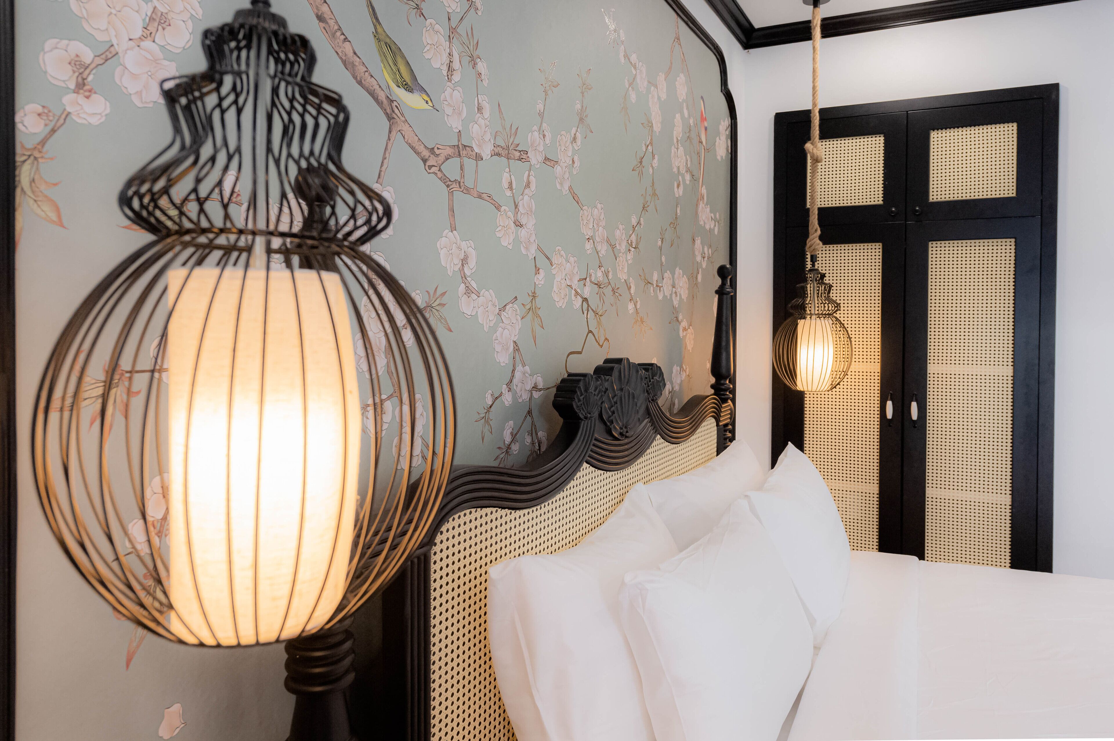 A bedroom with a bed, a wall-mounted lamp, and a door with a woven pattern.
