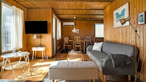 A cozy cabin interior with a sofa, a television, a dining area, and wooden walls. - 2 bedroom stunning home in Vordingborg (Vordingborg)