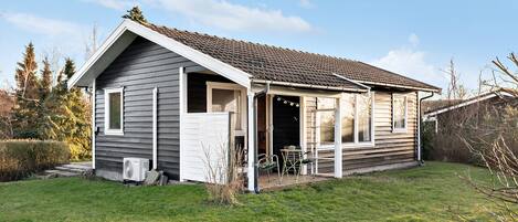 A single-story house with a covered porch, a small outdoor seating area, and a visible air conditioning unit.