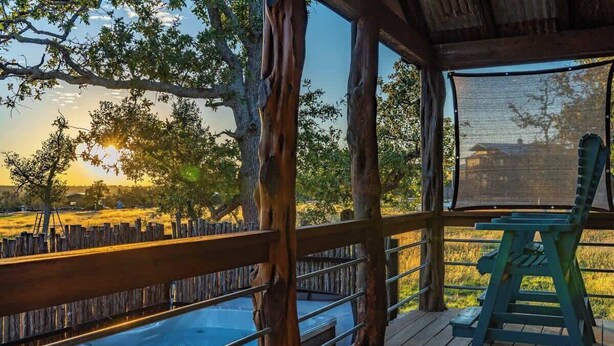 Una terraza de madera con vistas a un campo, un jacuzzi y una silla.