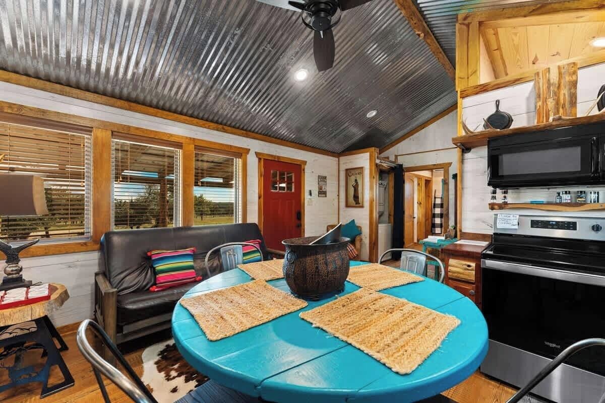 Un intérieur chaleureux avec une table ronde, un canapé, une cheminée et un coin cuisine.