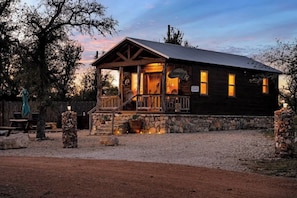 Un rustico chalet con veranda, fondamenta in pietra e facciata in legno.