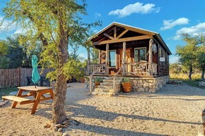 Eine Holzhütte mit Veranda, Picknicktisch und Baum.