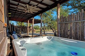 A hot tub under a wooden pergola with a view of trees and a wooden fence. - Rockin' R - Mason Jar Cabin (Fredericksburg)