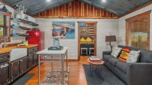A rustic cabin interior with a kitchen, dining area, and living room. - Rockin' R - Mason Jar Cabin (Fredericksburg)