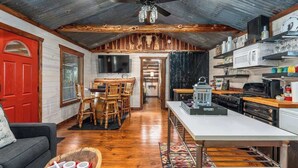 A rustic interior with a dining area, kitchen, and a red door. - Rockin' R - Mason Jar Cabin (Fredericksburg)