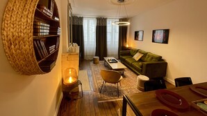 A cozy living room with a green sofa, a bookshelf, and a dining area with a wooden table and chairs. - Distinguished Townhouse, "L'Aparté" (Verdun)