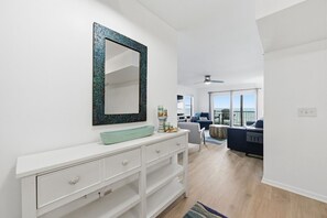 A modern living room with a white console table, a large mirror, and a view of the ocean through large windows.