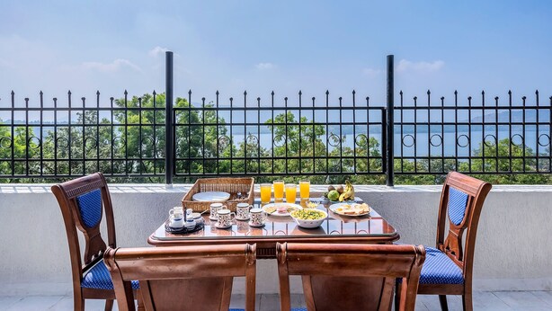 A balcony with a table set for breakfast, including plates, cups, and a basket. - CosmicStays Venus Villa- Private pool  (Mawal)