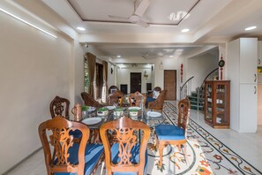 A dining area with a round table, chairs, and a staircase in the background. - CosmicStays Venus Villa- Private pool  (Mawal)
