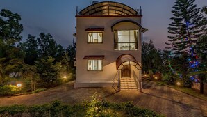 A two-story building with a curved roof, large windows, and a staircase leading to the entrance. - CosmicStays Venus Villa- Private pool  (Mawal)