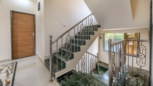 A staircase with marble steps and metal railings, a wooden door, and a patterned rug on the floor. - CosmicStays Venus Villa- Private pool  (Mawal)