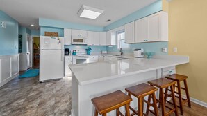 Une cuisine moderne avec des meubles blancs, un grand îlot central doté de tabourets et une palette de couleurs vives.