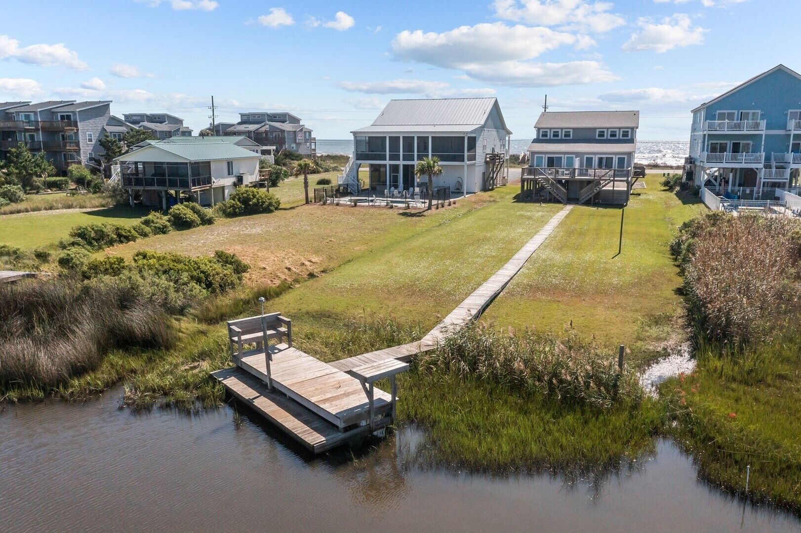 A coastal property with multiple buildings, a dock, and a grassy area.