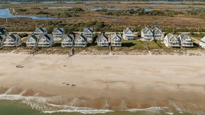 A beachfront property with multiple houses, a sandy beach, and a marshy area in the background. - 6BR Oceanfront House in North Topsail Beach w Hot Tub, Community Pool, Sleeps 15 (North Topsail Beach)