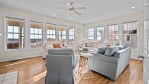 A spacious living room with large windows, a ceiling fan, and a view of the ocean. - Island Drive 4158 (North Topsail Beach)