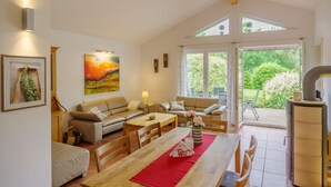 A spacious living room with a dining area, a sofa set, a wooden table, and a kitchen area with a stove.